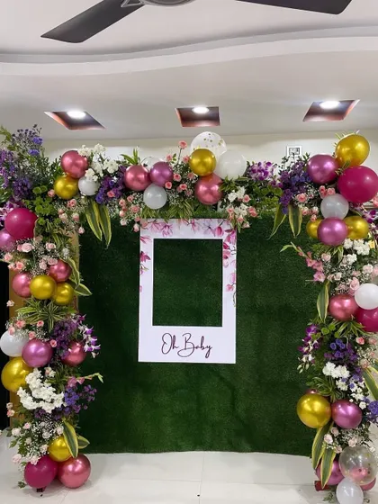 A fun and interactive photo booth I designed for a baby shower. The backdrop features a lush green wall, a floral and balloon arch, and a custom "Oh Baby" polaroid frame.