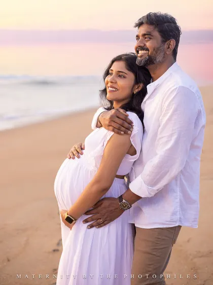 A beautiful, smiling portrait of the couple looking out at the ocean, dreaming of the family they are about to become.