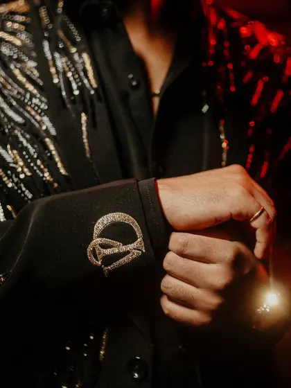 A detailed shot focusing on the custom monogram on the groom's cuff. Capturing these personalized details is part of telling a complete and unique wedding story.