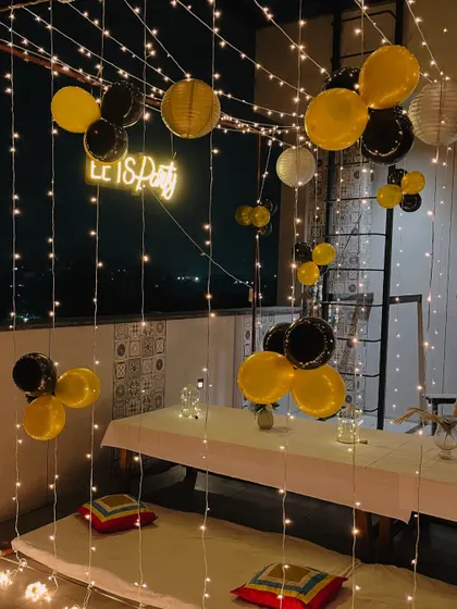 A view of the rooftop party setup, showing the low seating arrangement under a ceiling of fairy lights and balloons.