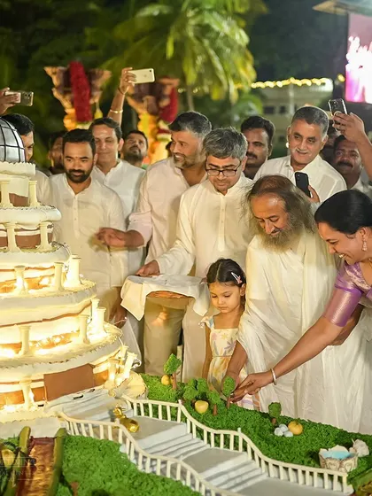 Gurudev, along with a young devotee, cuts a magnificent cake shaped like the Vishalakshi Mantap for his 68th birthday. It was a moment of pure joy and celebration.