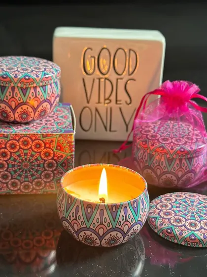 A vibrant mandala-print tin jar candle, shown both open and closed. These are great for budget-friendly festive hampers.
