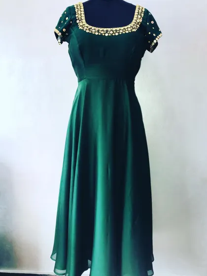 A simple yet beautiful dark green gown made from a plain saree. The custom look is elevated with a hand-embellished neckline and sleeves.