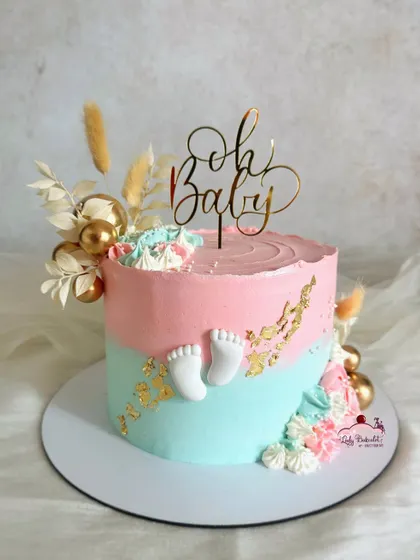 Oh baby! A lovely pink and blue baby shower cake with tiny fondant baby feet, gold leaf, and dried florals.