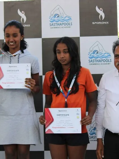 The top finishers in a girls' swimming event, smiling with their medals.