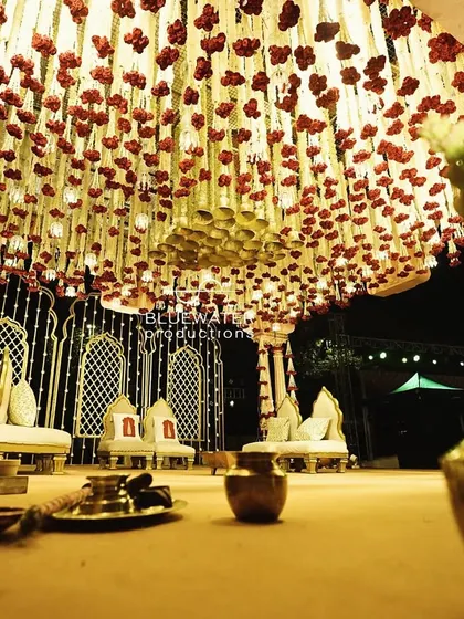 A low-angle view from the mandap, looking up at a dense ceiling of hanging red and white florals, creating a rich, textured canopy for the ceremony.