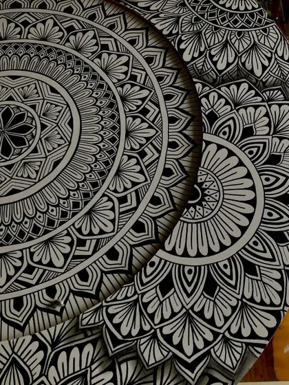 A close up of the details on the layered mandala. The design is split between two circular boards, creating a sense of depth and a crescent moon shape in the negative space.