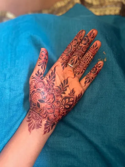 A beautiful floral mandala design on the palm. The combination of bold petals and delicate leafy vines creates a balanced and attractive look, with the stain showing a lovely dark color.