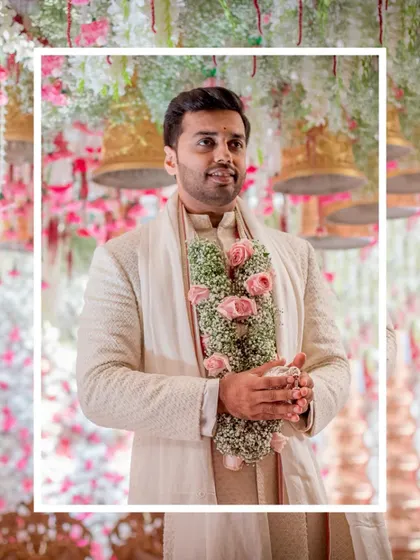 The groom, waiting for his bride. This portrait captures his anticipation, standing under the beautifully decorated mandap with a floral garland in hand.