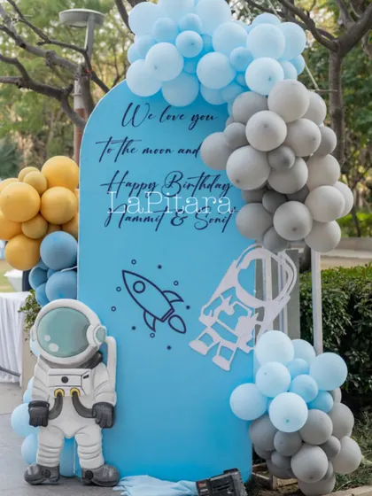 A sweet and personal welcome sign for a space-themed party, reading 'We love you to the moon and back', adorned with astronaut cutouts and a balloon galaxy.