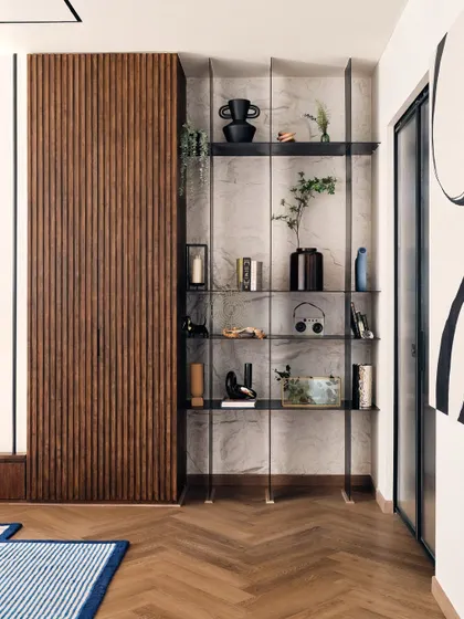 A sleek, modern shelving unit provides space for decor and books, set against a marble-effect wall. The combination of wood, metal, and stone creates a sophisticated, layered look.