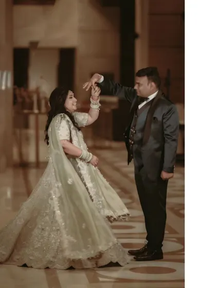 A joyful moment of dance. Gagan twirls Shalini in the elegant hotel lobby, her lehenga flowing as they share a happy, spontaneous moment.