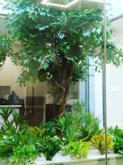 I provide realistic, large-scale artificial trees for indoor spaces. This tree is installed inside a glass enclosure in an office, adding a touch of nature to the corporate environment without any need for sunlight or water.