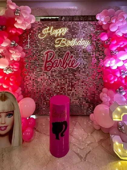 A vibrant Barbie theme party featuring a pink sequin wall, a neon 'Happy Birthday Barbie' sign, and columns of pink balloons.