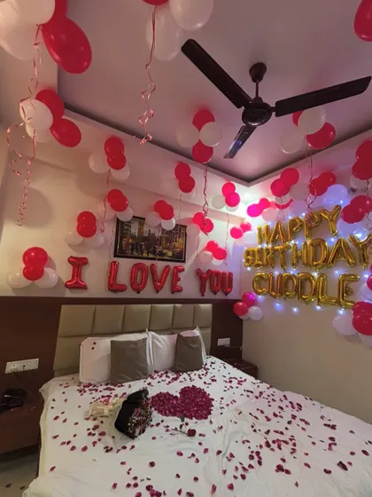 Another angle of the red and white themed romantic room decoration, showing balloons on the ceiling and fairy lights.