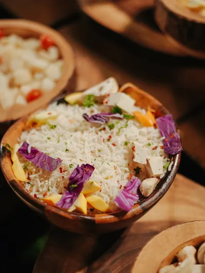 A beautifully presented bowl of rice, garnished with edible flowers and fresh vegetables. Even simple dishes are given an artistic touch to enhance the overall feast.
