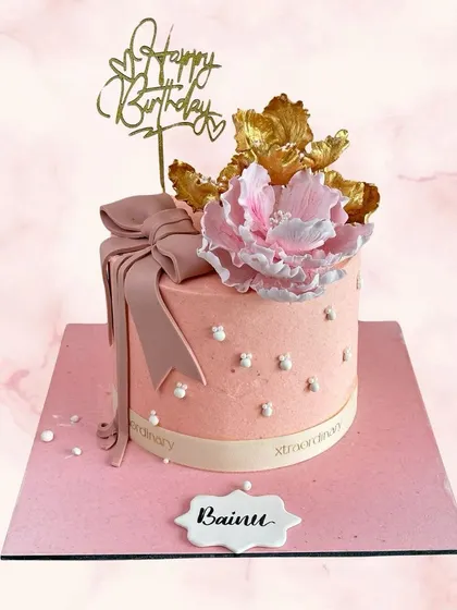 Pretty in pink for Bainu's birthday. This elegant cake features a large, handcrafted peony, a soft pink bow, and delicate pearl details.