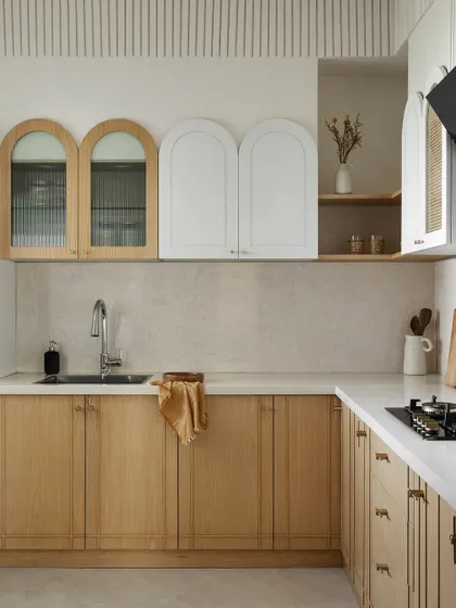 This kitchen uses a soft, neutral palette of light wood and white. The arched cabinet doors add a gentle, classic touch, while the clean lines keep the overall feel modern and uncluttered.