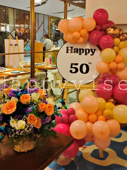 Celebrating a 50th birthday in style. This setup combines a vibrant balloon garland in sunset colors with a large, fresh floral arrangement, showing how I can create sophisticated and classy decor for important milestone events.