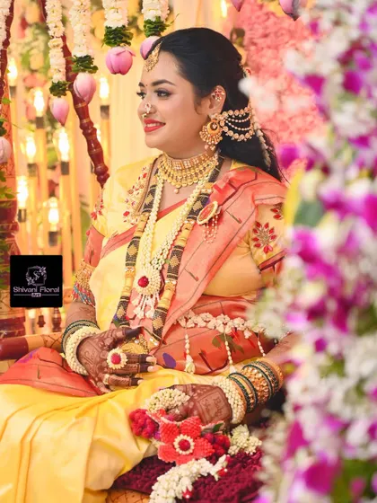 A beautiful portrait of a mom-to-be on her special day, adorned with a full floral jewellery set featuring red accents and a matching hand prop.