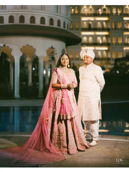 A classic, full-length portrait of the bride and groom in their wedding attire. The elegant backdrop and their happy expressions make this a timeless keepsake.
