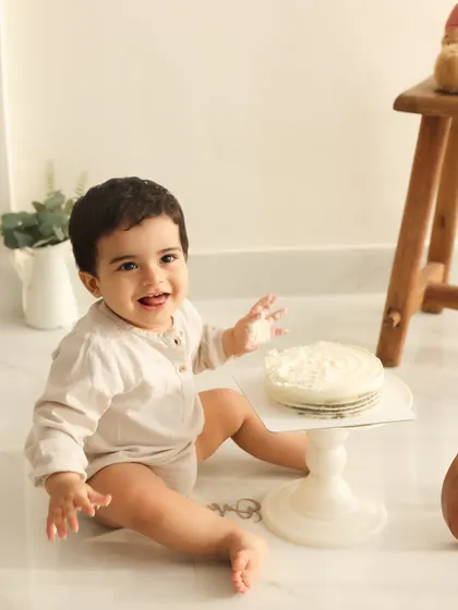 Ready for cake. This image captures the anticipation just before the cake smash begins. The simple, clean setup keeps the focus on the adorable birthday boy.