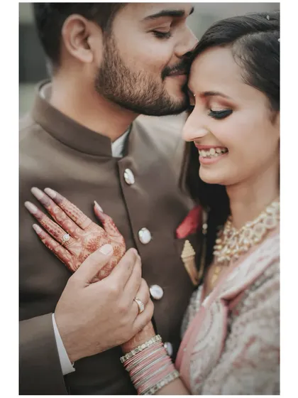 The groom gently holds the bride's hand, showing off her beautiful henna and engagement ring. This shot is all about the details and the connection they represent.