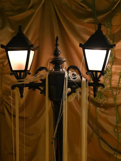A close-up of a classic double lamppost adorned with delicate ribbon streamers. This simple addition adds a touch of whimsy and movement to a classic decor piece.