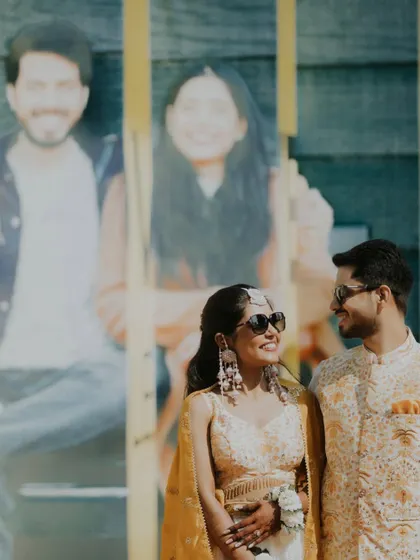 A creative shot of the couple during their Haldi, framed by a poster from their past, symbolizing their journey together.