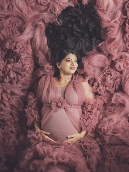 Radiant mama-to-be, enveloped in a sea of soft, ruffled pink fabric. This stunning top-down portrait showcases the beauty of motherhood in a unique and artistic way.