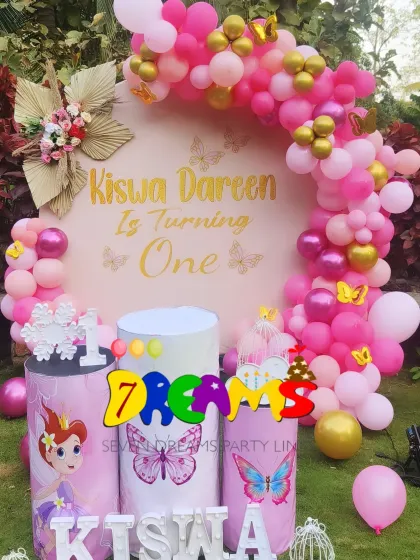 An outdoor butterfly-themed party setup. I used a vibrant pink balloon arch and custom-printed pedestals with butterfly and fairy graphics to create a bright and cheerful look.