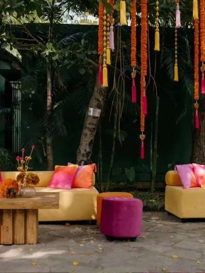 The lounge area is set under trees decorated with hanging floral tassels.
