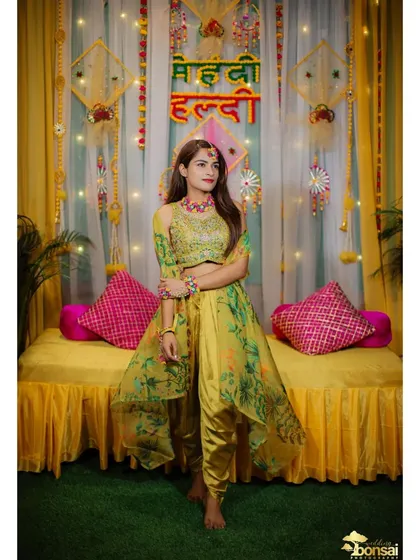 A full-length shot of the bride in her vibrant Haldi outfit, posing against the festive decor.