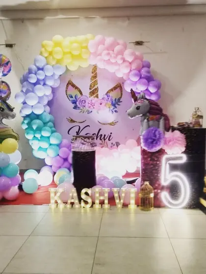 A simple and sweet unicorn theme for Kashvi's 5th birthday. This setup includes a pastel rainbow balloon arch, a unicorn backdrop, and a light-up number "5" for a touch of magic.