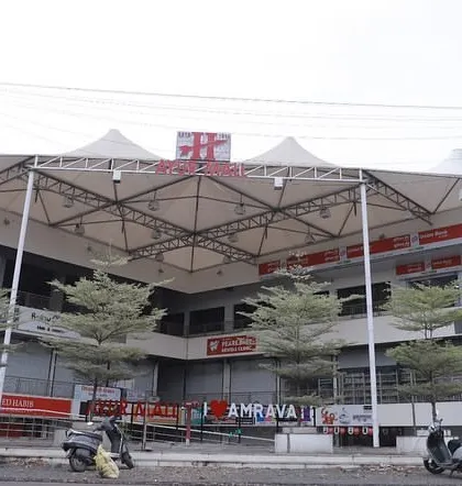 A street-level view of the completed Ayur Mall, showing the prominent tensile roof structure that covers the central atrium. This architectural element provides shelter while allowing natural light, creating a bright and welcoming food court and plaza area.