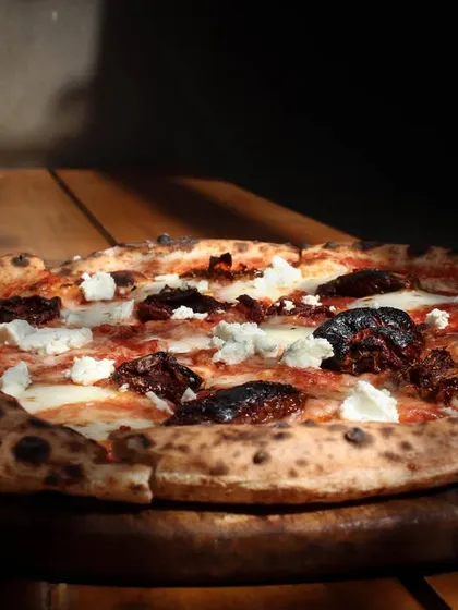 Our Smokey Marzano pizza soaking up the sun. It features a classic combination of sundried tomatoes, garlic, feta, and our hand-stretched mozzarella on a sourdough base.