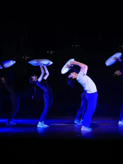 Four dancers perform a synchronized sequence in "ME & MY PILLOW." The stark blue lighting and the use of pillows as expressive props create a visually striking and emotionally charged atmosphere.