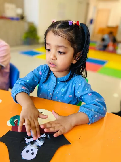 A girl carefully glues pieces onto her pirate-themed craft. This activity is excellent for building hand-eye coordination and patience.