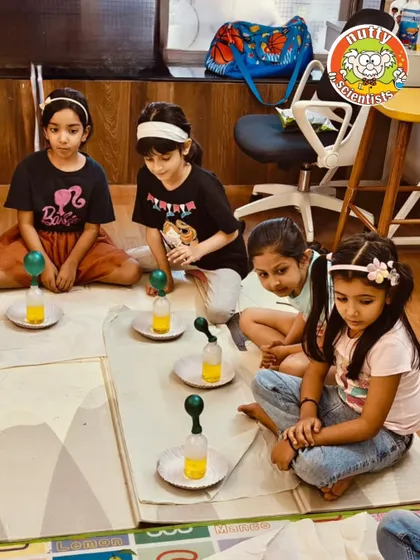 A group of girls watch their bottle-and-balloon experiments, learning about the gas produced from a simple chemical reaction between vinegar and baking soda.