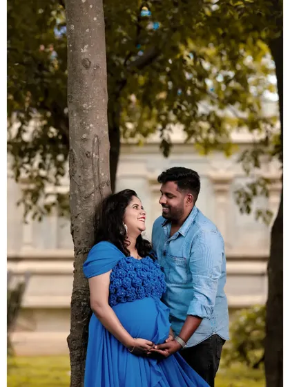 A sweet and intimate couple's moment during a maternity shoot. The sky blue tail gown complements the partner's casual blue shirt for a coordinated look.