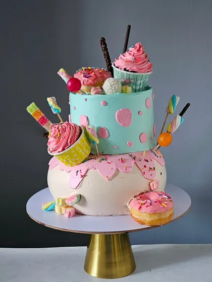 Another angle of the fun and fluffy candyland cake, showing the playful arrangement of sweets on a gold cake stand.