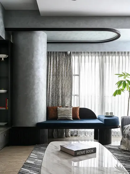 We believe architectural challenges are design opportunities. This custom-designed curved seating, finished in a bold blue fabric, elegantly wraps around a structural column, transforming it from an obstruction into a stunning and functional focal point in the living room.