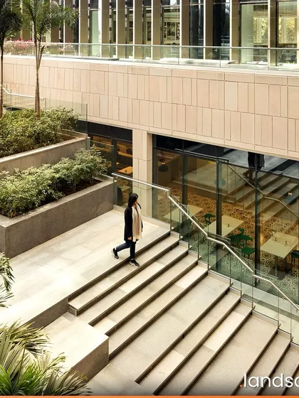 The landscape design for Zydus Headquarters includes multi-level terraced courts that echo traditional Indian stepwells. These spaces provide shaded public areas for employees, with integrated planters and palm trees that enhance the connection to nature within the corporate environment.