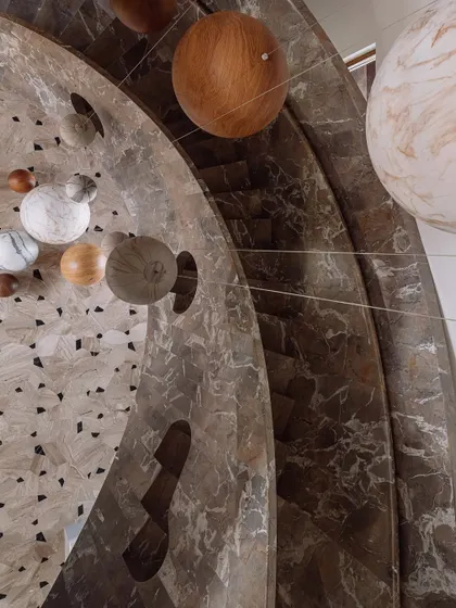 Details are where the story lives. This sculptural staircase is more than just a way to move between floors; it's a celestial experience, with an installation of wooden and marble spheres that hang like a confetti carnival within the marble-clad stairwell.