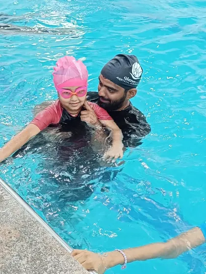 A coach gently guides a young swimmer, demonstrating the supportive instruction that helps children overcome fear.