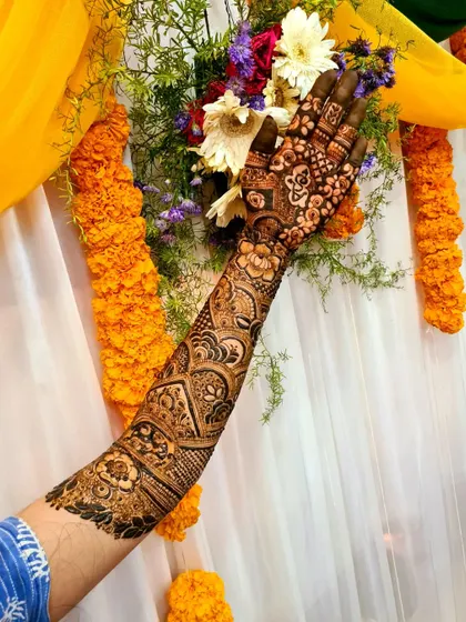 A single-arm bridal design for Simran, set against a festive backdrop of marigolds. The artwork is a mix of traditional Indian motifs.