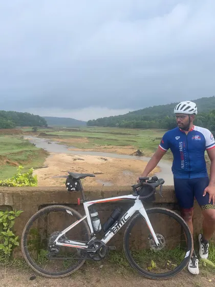 A rider and his bike against the backdrop of a muddy river during the Jog Falls 1000K BRM. The monsoon season brings its own unique beauty and challenges to the ride.