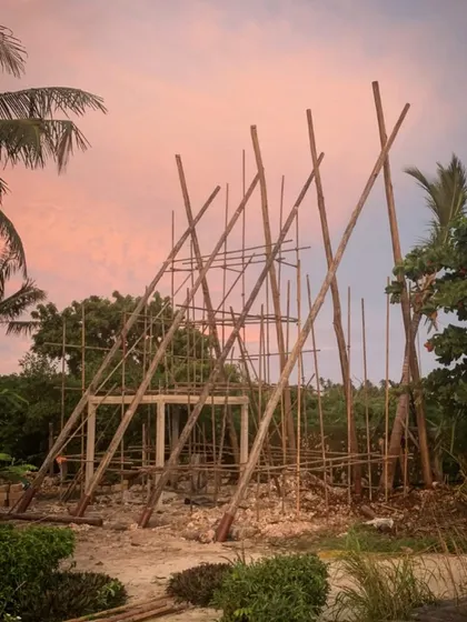 The early stages of the spa construction at Kizikula. The scaffolding, made from local timber, creates a beautiful, sculptural form against the sunset sky, hinting at the A-frame structure to come.