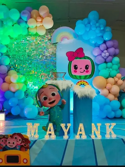 A vibrant Cocomelon party with a sparkling sequin wall. The mix of colorful balloons, character cutouts, and the shimmering backdrop creates a super fun and photogenic spot for a first birthday.