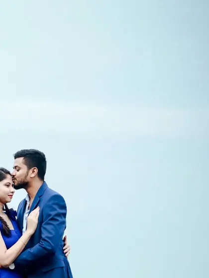 A groom-to-be looking handsome in a classic blue suit, sharing a tender moment with his fiancée during their pre-wedding shoot.